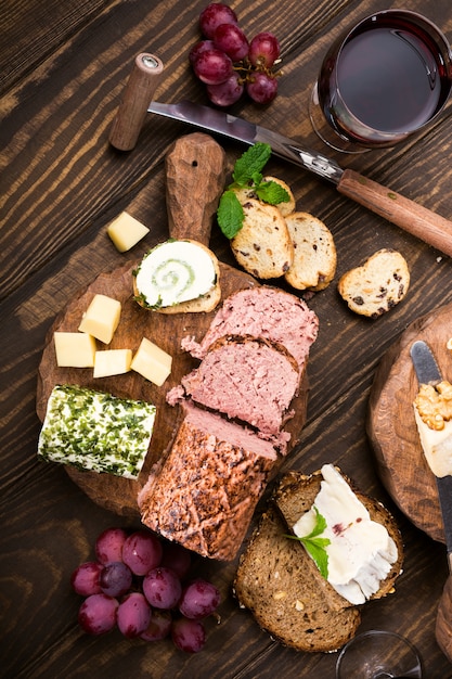 Sortierte Käse auf hölzernen Brettern Platte, Trauben, Brotwein und Pastete