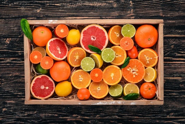 Sortierte Zitrusfrüchte in einer Holzkiste Orange Mandarine Grapefruit Zitrone Auf einem hölzernen Hintergrund Ansicht von oben Kopieren Sie Platz