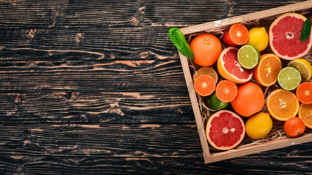 Sortierte Zitrusfrüchte in einer Holzkiste Orange Mandarine Grapefruit Zitrone Auf einem hölzernen Hintergrund Ansicht von oben Kopieren Sie Platz