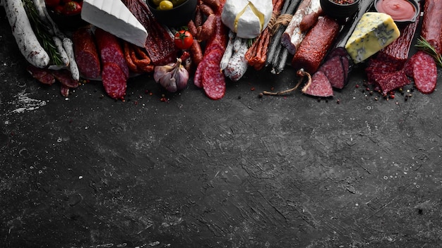 Sortiment von Käse Salami Wurst Gewürze und Fleischprodukte auf schwarzem Hintergrund Ansicht von oben Freier Platz für Ihren Text