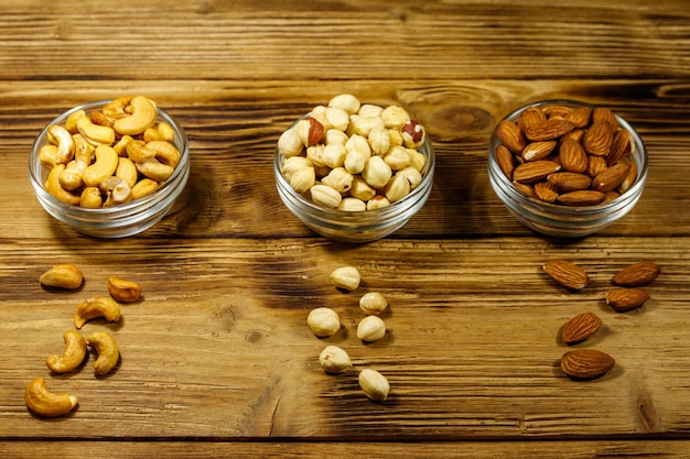 Sortiment von Nüssen auf Holztisch Mandel Haselnuss und Cashew in Glasschalen Konzept für gesunde Ernährung