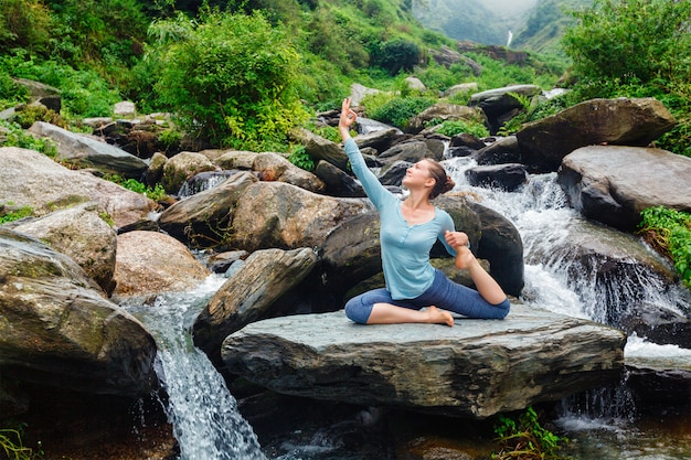 Sorty cabe mulher fazendo yoga asana ao ar livre na cachoeira tropical