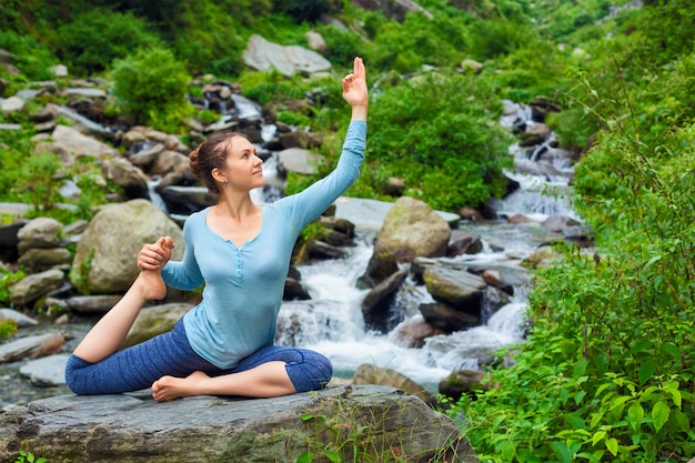 Sorty fit mujer haciendo yoga asana al aire libre en cascada tropical