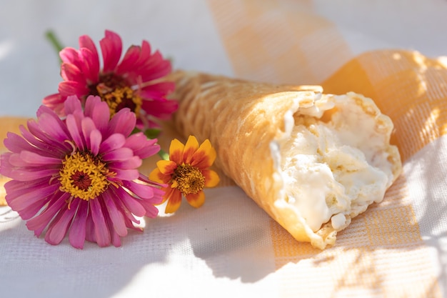 Sorvete artesanal em casquinha de waffle e pequeno buquê de flores em guardanapo de linho em dia quente de verão