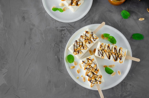 Sorvete caseiro com torrone, caramelo e amendoim no palito com folhas de hortelã