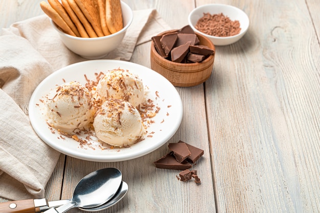 Foto sorvete cremoso com gotas de chocolate e biscoitos em uma parede bege clara. vista lateral, copie o espaço.