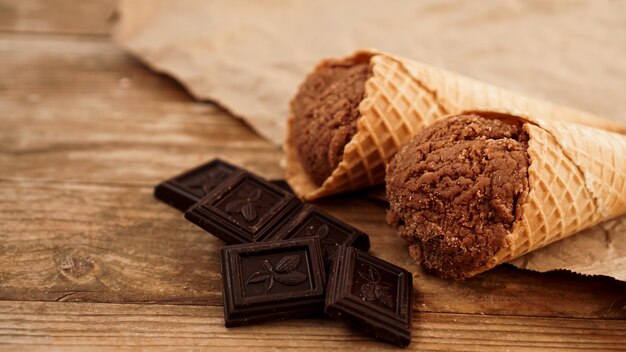 Sorvete de chocolate em casquinha de waffle em papel artesanal em um fundo de madeira