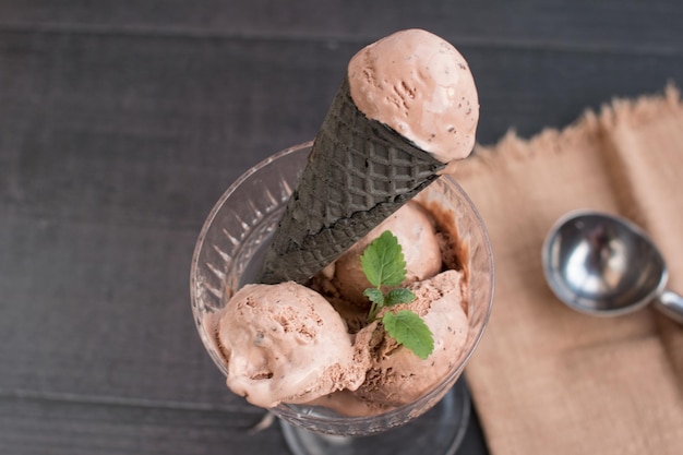 Foto sorvete de chocolate em um cone de waffle preto sobremesa de chocolate com paus de canela em um fundo preto