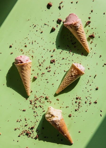 Sorvete de creme, morango e chocolate quebrado e derramado sobre fundo verde. acima vista