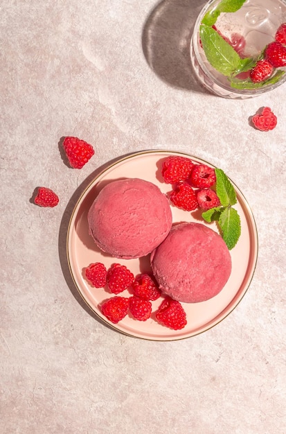 Sorvete de framboesa com framboesas frescas e hortelã no prato rosa sobre fundo rosa Sombras longas na moda luz ensolarada Vista superior