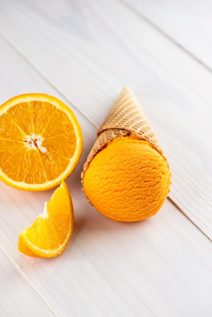 Sorvete de laranja em um cone de waffle em uma mesa de madeira