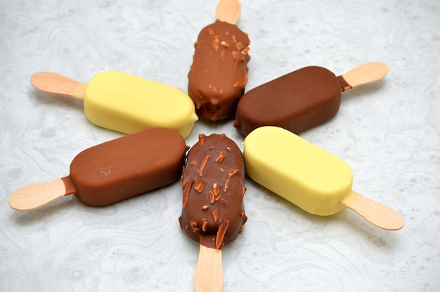 Sorvete sortido em cobertura de chocolate ao leite branco e chocolate amargo no palito