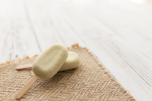 Sorvetes de biscoito brilhante branco em um palito na mesa de madeira.