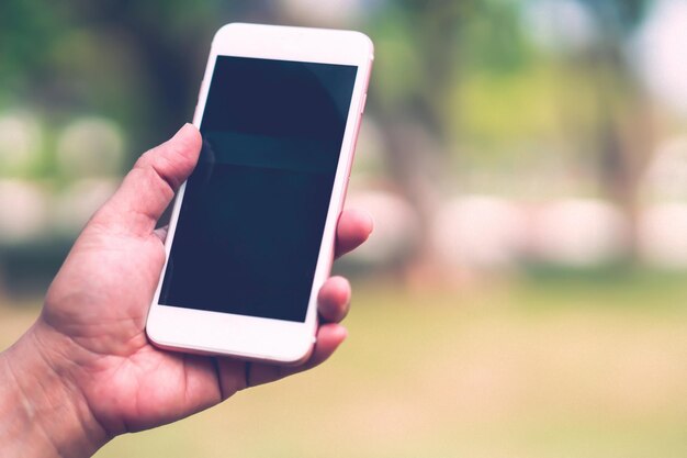 Sostener y usar un teléfono móvil inteligente para comunicarse al aire libre en el parque