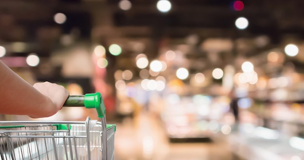 Foto sostenga el carrito de la compra del supermercado con los estantes de las tiendas