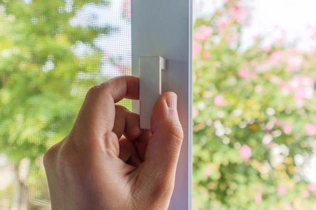 Foto sostenga a mano la manija de la pantalla de alambre de mosquitera en la ventana de la casa