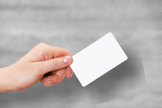 Sostenga a mano una maqueta de tarjeta translúcida en blanco con esquinas redondeadas.