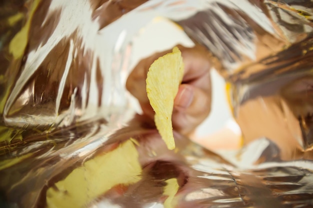 Sostenga a mano papas fritas dentro de una bolsa de aluminio para refrigerios