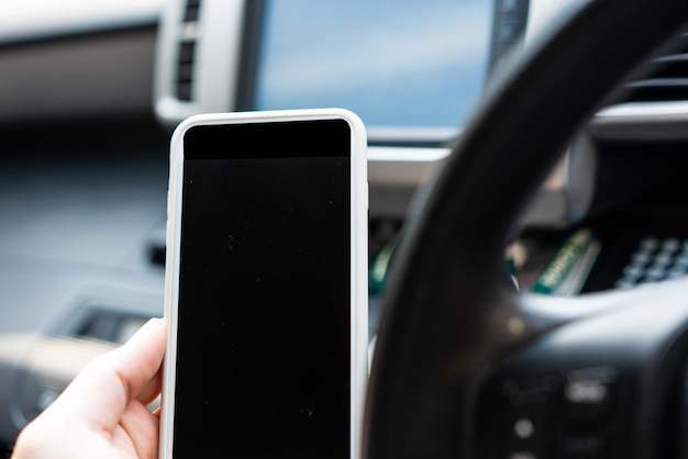 Sostenga a mano el teléfono móvil en blanco en el automóvil para obtener tecnología