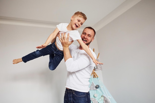 Sosteniendo al niño en las manos El padre y su joven joven pasan tiempo juntos en el interior cerca de la tienda