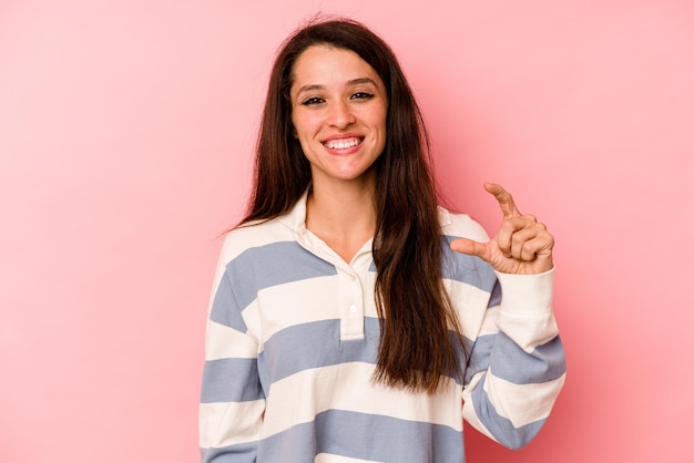 Sosteniendo algo pequeño con los dedos índice sonriendo y confiado