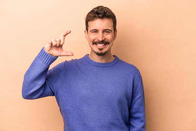 Sosteniendo algo pequeño con los dedos índices sonriendo y confiado