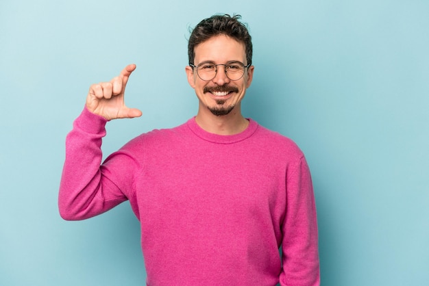 Sosteniendo algo pequeño con los dedos índices sonriendo y confiado