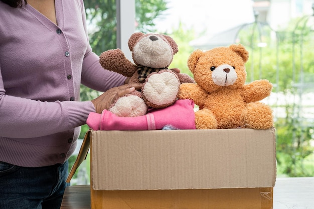 Foto sosteniendo una caja de donación de ropa con ropa usada y muñecas en casa para ayudar a los pobres del mundo