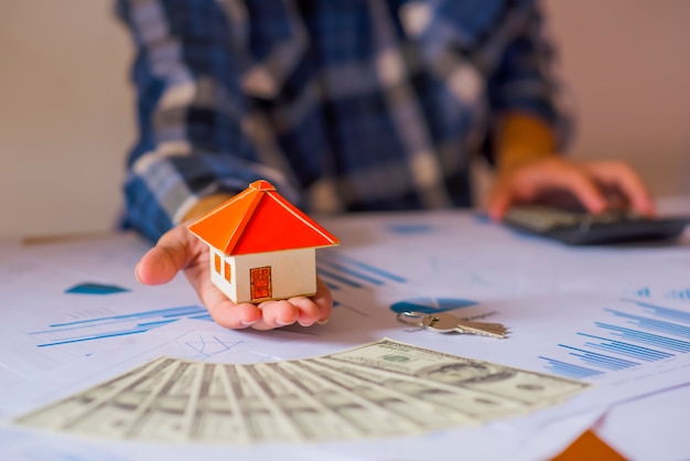 Foto sosteniendo la casa que representa la propiedad de la vivienda y el negocio inmobiliario.