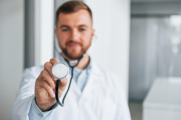 Foto sosteniendo estetoscopio médico profesional en bata blanca está en la clínica