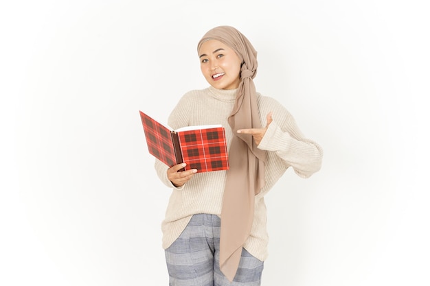 Sosteniendo el libro de hermosa mujer asiática vistiendo Hijab aislado sobre fondo blanco.