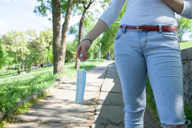 Sosteniendo una máscara médica en su mano en la calle