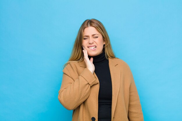 sosteniendo la mejilla y sufriendo dolor de muelas doloroso, sintiéndose enfermo, miserable e infeliz, buscando un dentista