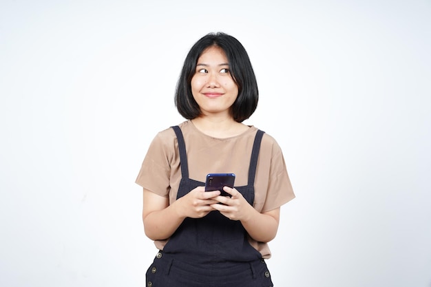 Sosteniendo o usando el teléfono inteligente y la sonrisa de una hermosa mujer asiática aislada en el fondo blanco