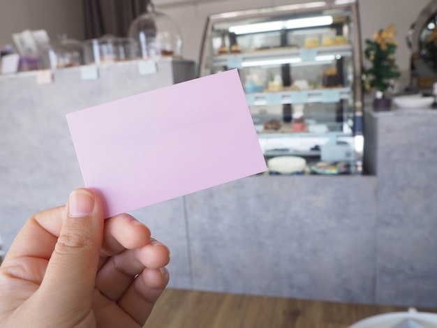 Sosteniendo un papel rosa con fondo de cafetería