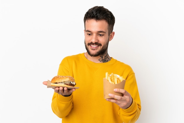 Sosteniendo patatas fritas y hamburguesa con queso sobre fondo aislado