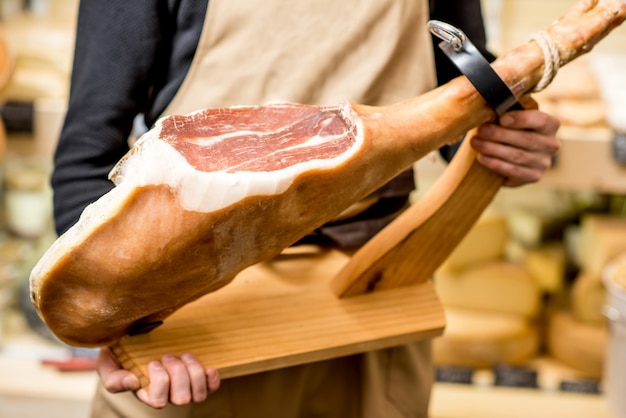 Sosteniendo la pierna prosciutto incisa con soporte jamonero en la tienda