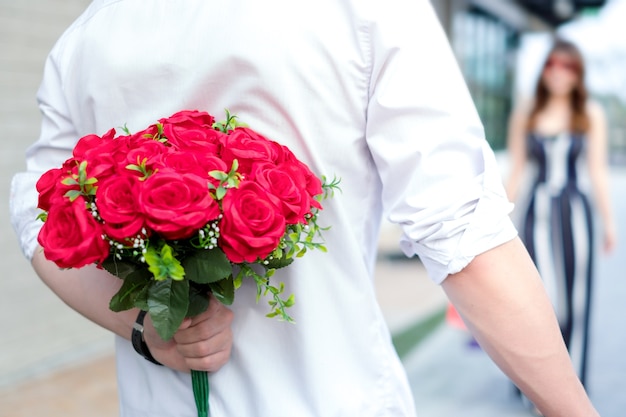 sosteniendo rosas rojas en las manos para sorprender a su novia