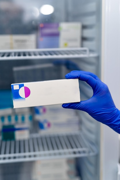 Sosteniendo tabletas médicas en la mano con guante. Caja de farmacia de pastillas para el tratamiento de enfermedades.