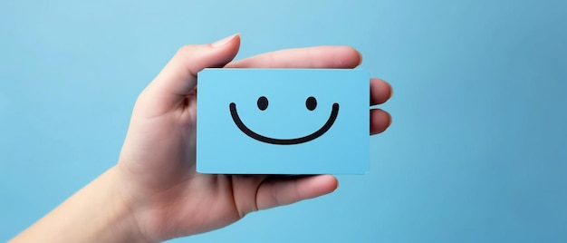 Foto sosteniendo una tarjeta de cara sonriente contra el azul