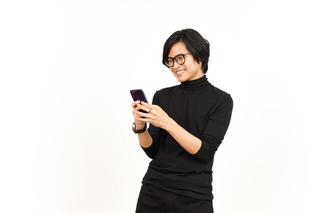 Sosteniendo y usando el teléfono inteligente con la cara sonriente del hombre asiático guapo aislado sobre fondo blanco