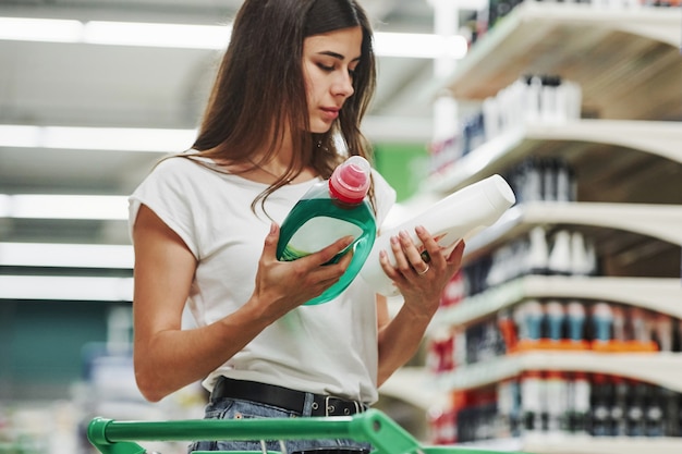 Sostiene el producto. Compradora femenina en ropa casual en el mercado.