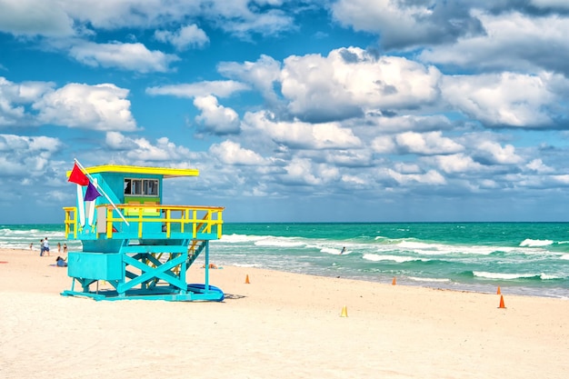 South Beach, Miami, Florida, Rettungsschwimmerhaus in einem farbenfrohen Art-Deco-Stil blau und gelb auf bewölktem blauem Himmel und Atlantik im Hintergrund, weltberühmter Reiseort