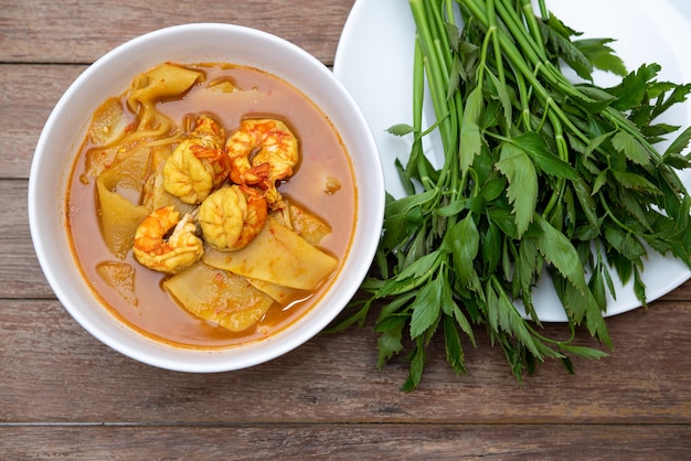 Southern Thai Spicy Sour Yellow Curry mit Garnelen oder Garnelen und eingelegtem Bambussprossen (Gaaeng Leuuang) mit Gemüse gegessen Wassertropfenkraut oder Oenanthe zum Verkauf im thailändischen Restaurant