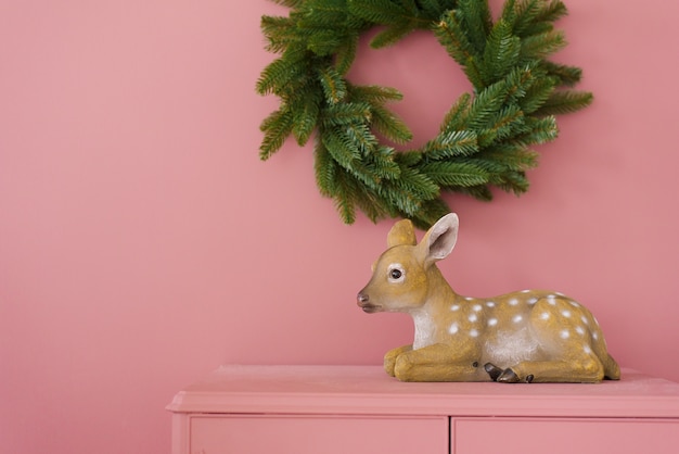 Souvenirkitz auf einer rosa Kommode gegen eine rosa Wand, an der ein Weihnachtsbaum hängt.