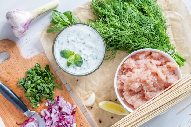 Souvlaki und Bestandteile, weißer hölzerner Hintergrund