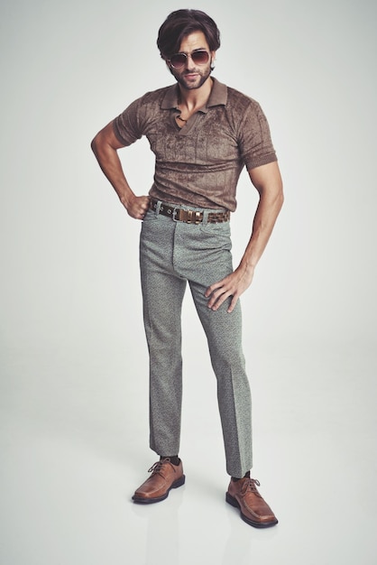 Soy una especie de gran cosa... Un hombre guapo con ropa retro de los años 70 haciendo una pose en el estudio.