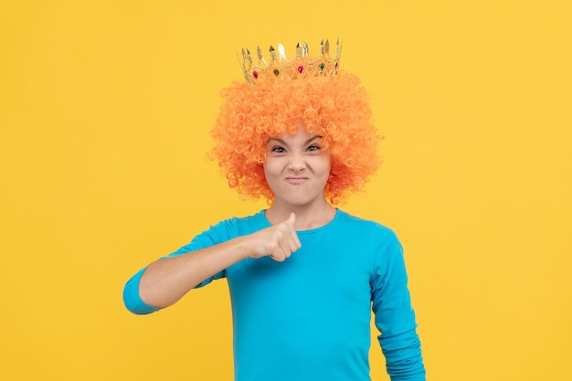 Soy el jefe. Niño egocéntrico con peluca de payaso y corona. Imagínese a sí misma como una princesa. Niña divertida con diadema. Chica adolescente egoísta en el concurso de tiara.