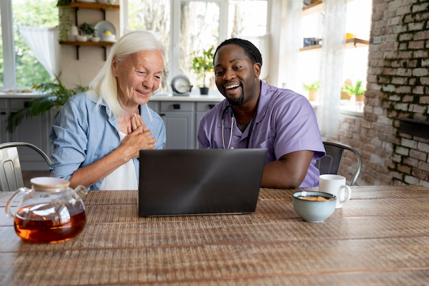 Sozialarbeiter, der mit einer älteren Frau auf einem Laptop schaut