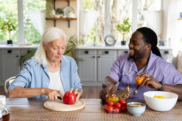 Foto sozialarbeiterin, die mit einer älteren frau essen macht